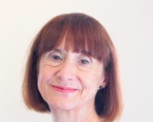 Photo of lady with dark redish bobbed hair with a fringe wearing a delicate necklace