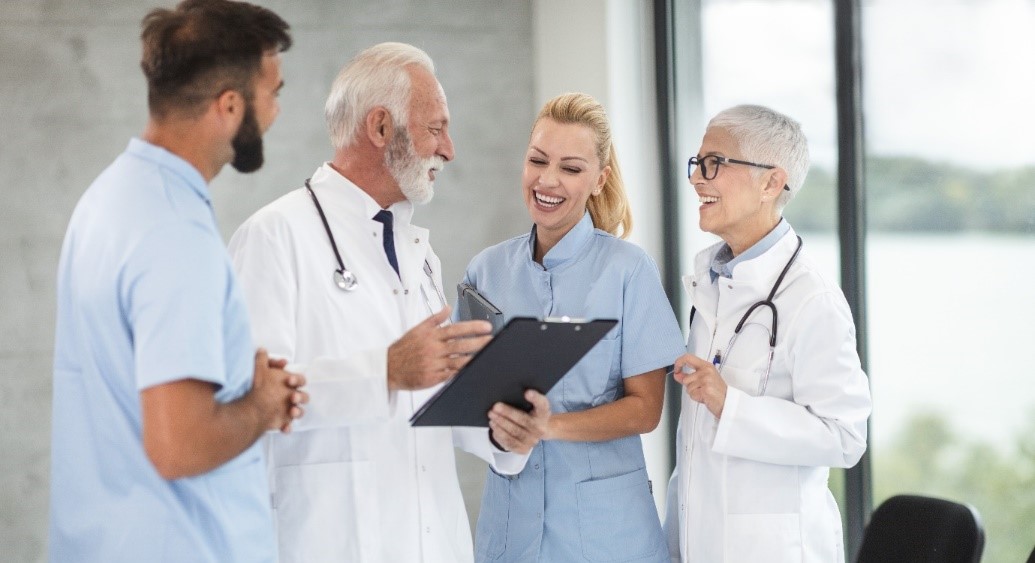 An image of four medical professionals in white or blue uniforms who appear to be having a discussion