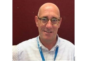 Photo of white male with glasses wearing a blue lanyard